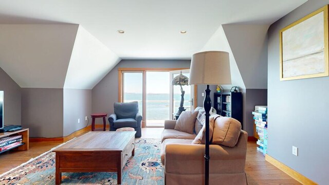 living room featuring a water view, lofted ceiling, and light hardwood / wood-style floors