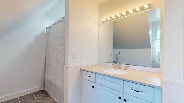 bathroom featuring a shower with curtain, tile patterned floors, lofted ceiling, vanity, and tile walls