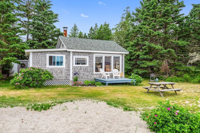 back of house featuring a shingled roof, a lawn, and a chimney