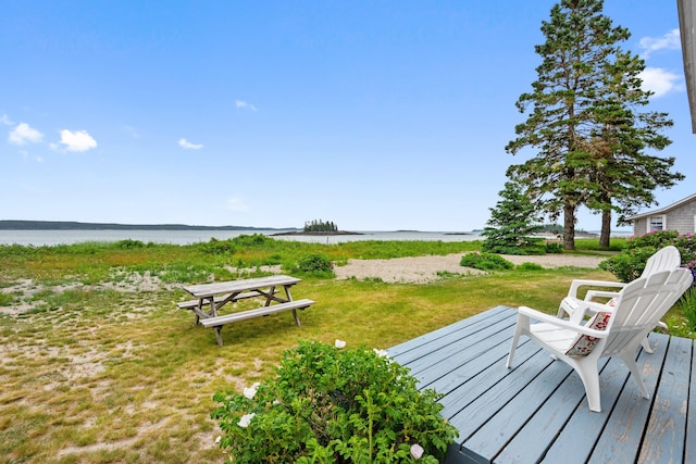 view of community with a deck with water view and a lawn