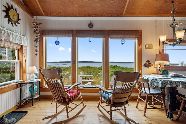 sunroom featuring a water view and a notable chandelier