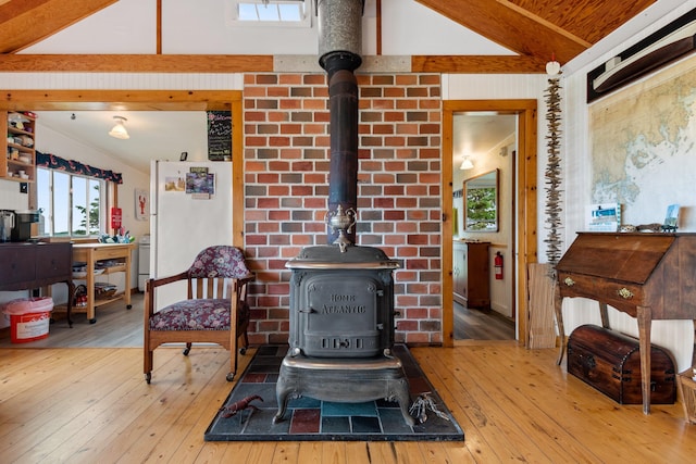 living room with vaulted ceiling with beams, light wood finished floors, and a wood stove