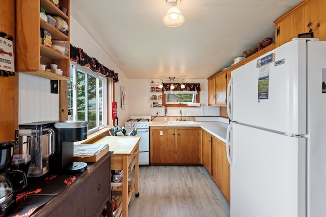 kitchen featuring brown cabinets, open shelves, light countertops, a sink, and white appliances