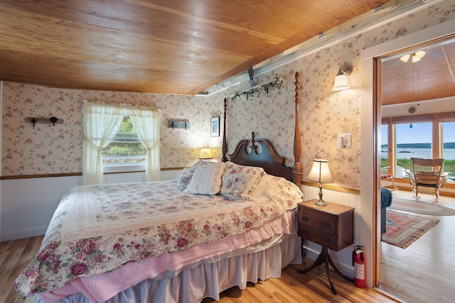 bedroom featuring a water view, hardwood / wood-style flooring, and wooden ceiling