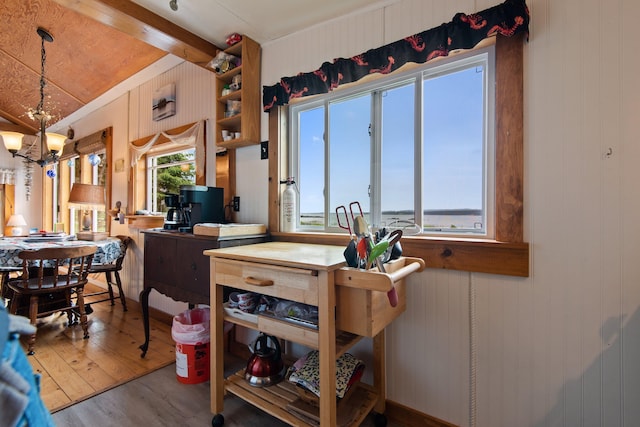 kitchen with hanging light fixtures, an inviting chandelier, lofted ceiling with beams, and wood finished floors