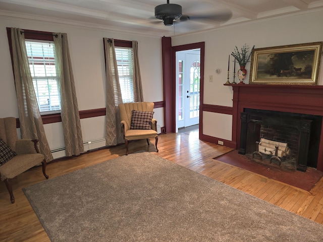 sitting room with hardwood / wood-style flooring, ceiling fan, ornamental molding, baseboard heating, and beamed ceiling