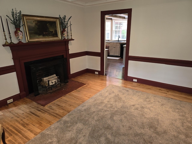 living room featuring crown molding, light hardwood / wood-style flooring, and sink