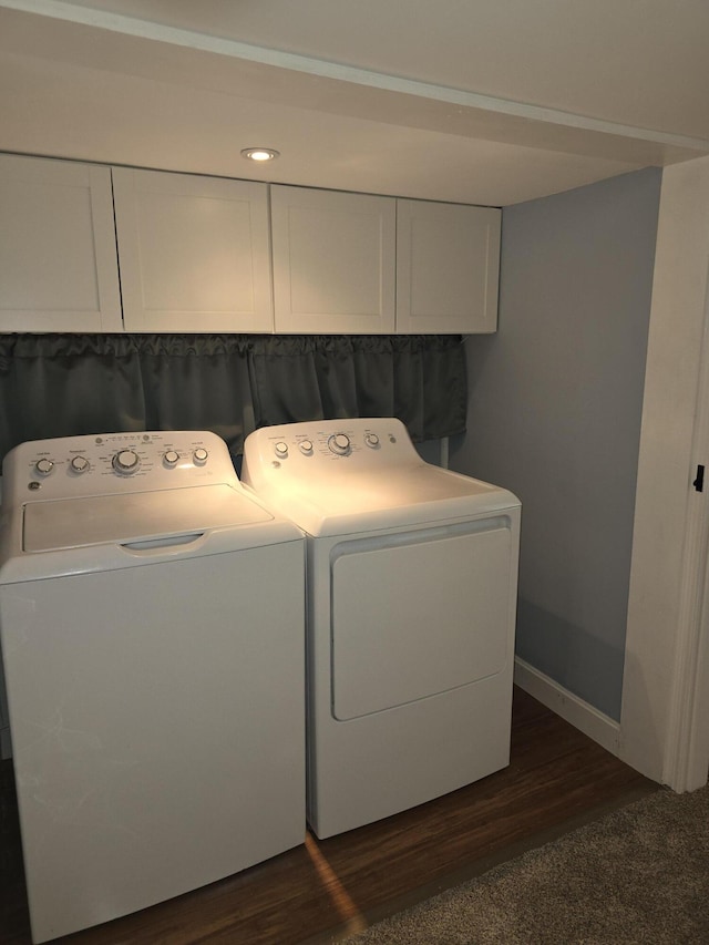 clothes washing area with dark hardwood / wood-style flooring, washer and clothes dryer, and cabinets