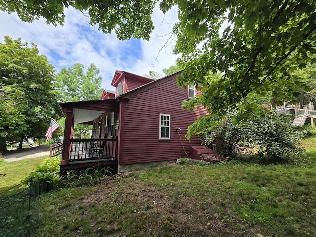 view of side of property featuring covered porch and a lawn