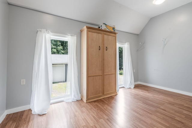 spare room with baseboards, lofted ceiling, a wealth of natural light, and light wood-style flooring