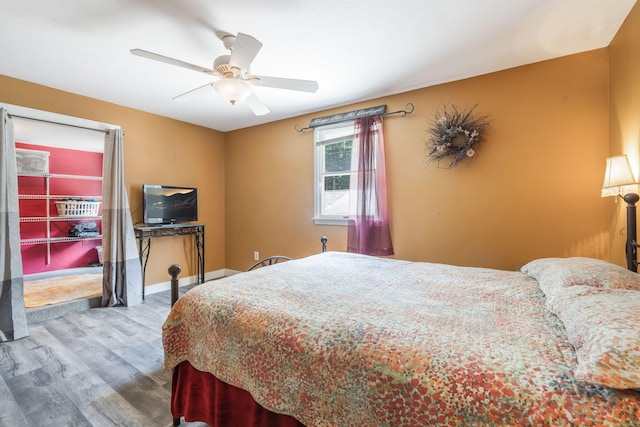 bedroom featuring baseboards, wood finished floors, and ceiling fan