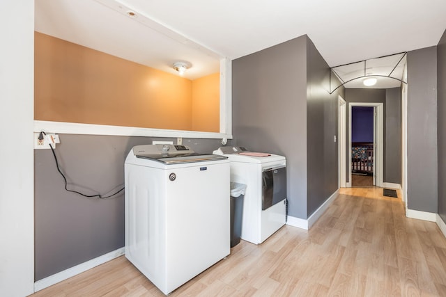 laundry area with baseboards, laundry area, washer and dryer, and light wood finished floors