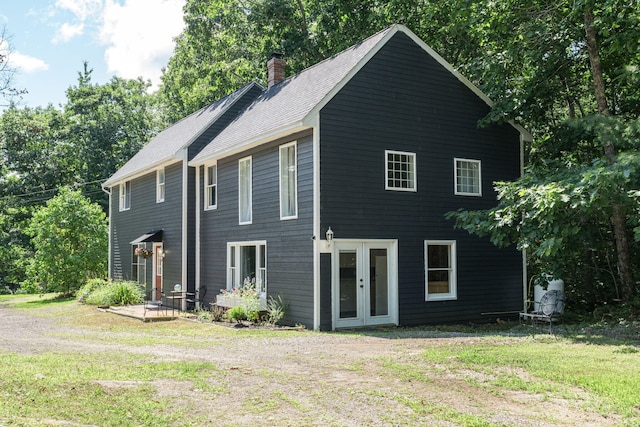 view of front of house featuring a chimney, a front yard, and french doors