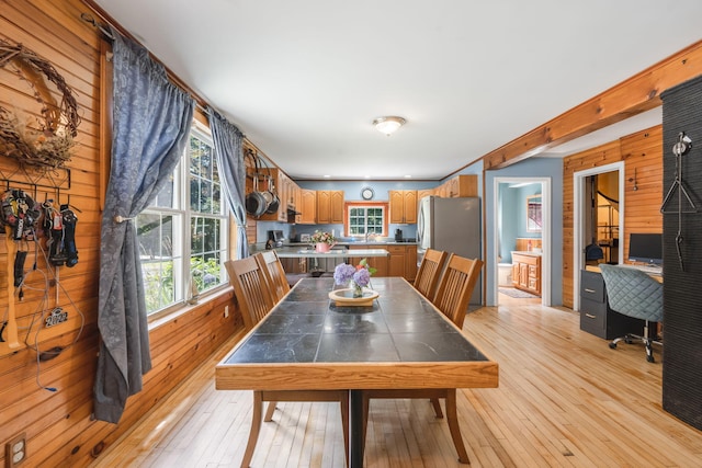 dining area with wood walls and light wood-style floors