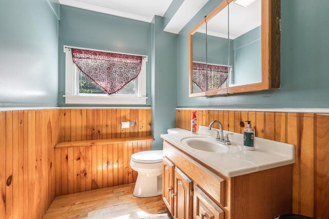 bathroom with vanity, wood walls, wainscoting, toilet, and wood finished floors