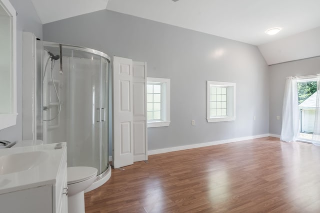 bathroom with vaulted ceiling, toilet, baseboards, a stall shower, and wood finished floors