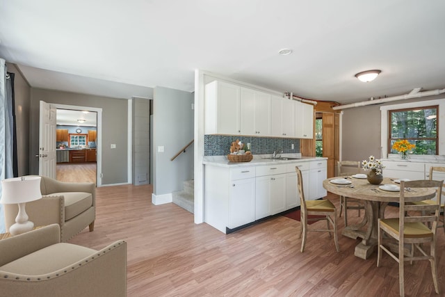 kitchen featuring light countertops, light wood-style floors, decorative backsplash, and white cabinets