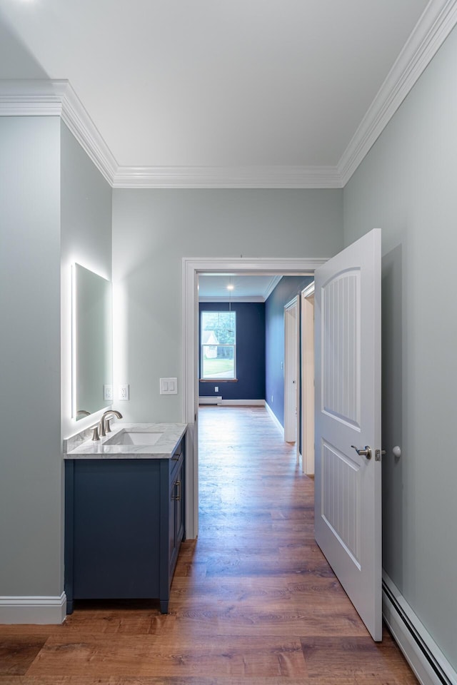 hallway featuring sink, ornamental molding, dark hardwood / wood-style floors, and a baseboard heating unit