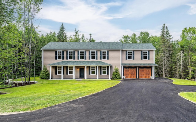 view of front of home with a front lawn, covered porch, and a garage