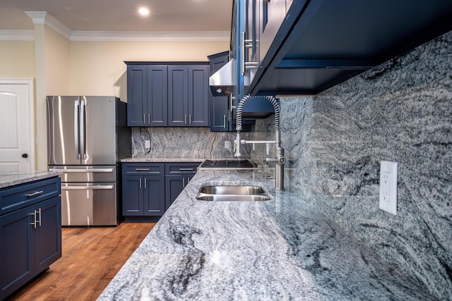 kitchen featuring blue cabinetry, stainless steel refrigerator, light stone countertops, hardwood / wood-style flooring, and ornamental molding