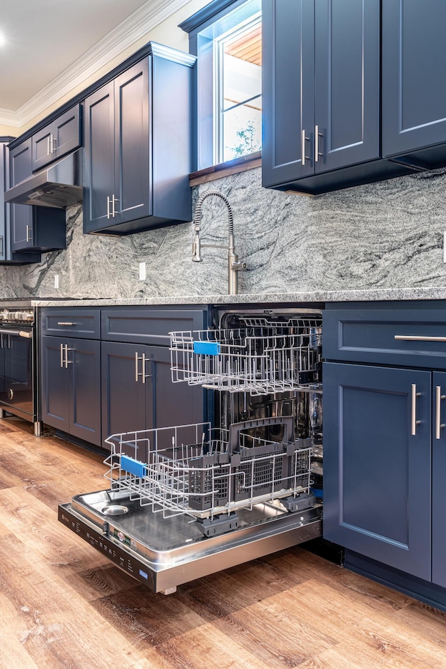 kitchen featuring light stone countertops, ornamental molding, blue cabinetry, tasteful backsplash, and light hardwood / wood-style floors