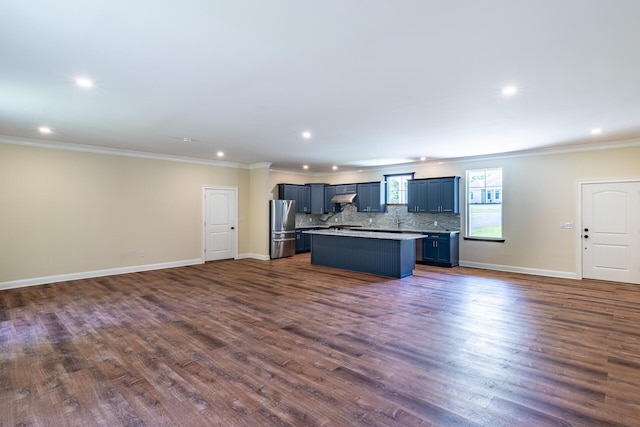 kitchen featuring a center island, dark wood-type flooring, extractor fan, ornamental molding, and stainless steel refrigerator