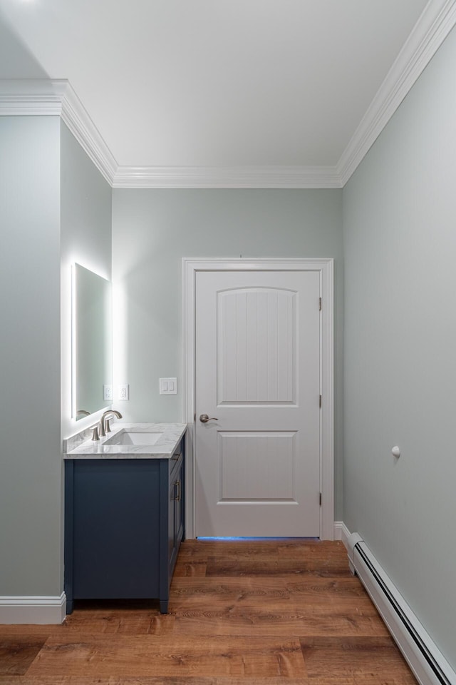 bathroom featuring hardwood / wood-style floors, vanity, a baseboard radiator, and crown molding