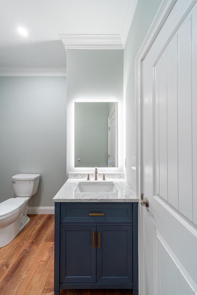 bathroom featuring wood-type flooring, vanity, toilet, and crown molding