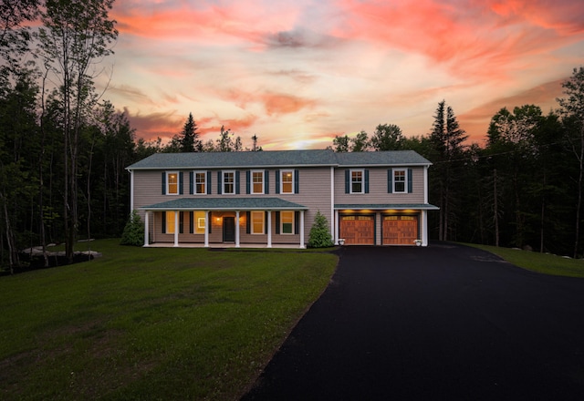 colonial-style house with a lawn, a porch, and a garage