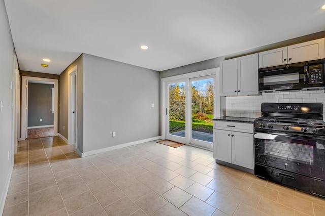 kitchen featuring white cabinetry, decorative backsplash, dark stone counters, light tile patterned floors, and black appliances