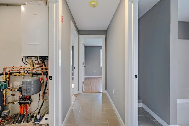 corridor featuring water heater and light tile patterned floors