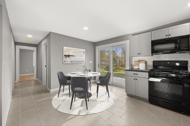 kitchen with tasteful backsplash, white cabinetry, light tile patterned floors, and black appliances