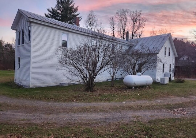 property exterior at dusk featuring a lawn