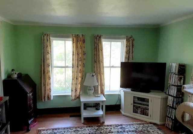 living area with plenty of natural light, ornamental molding, and light hardwood / wood-style flooring