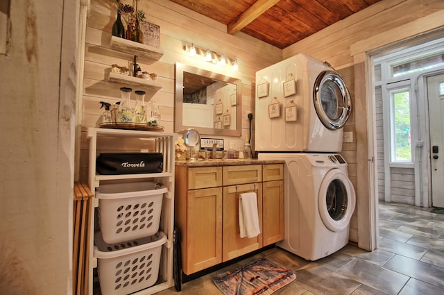 clothes washing area with stacked washer / drying machine, sink, wooden walls, and wooden ceiling