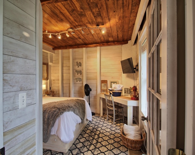 bedroom with wood ceiling, rail lighting, and wood walls