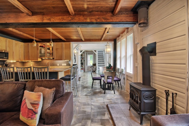 living room with wood ceiling, a wood stove, and beam ceiling