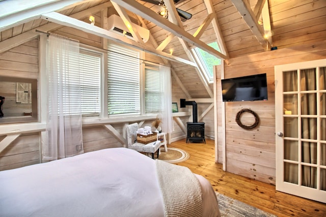 bedroom featuring hardwood / wood-style flooring, a wood stove, multiple windows, and wood walls