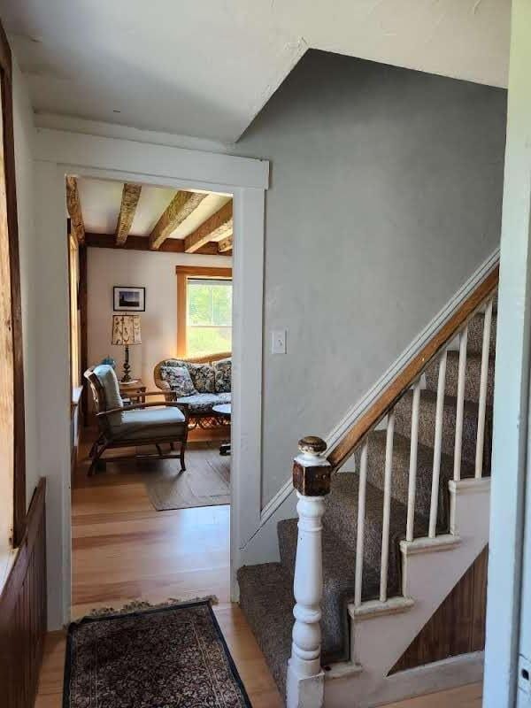 stairs featuring hardwood / wood-style flooring and beam ceiling