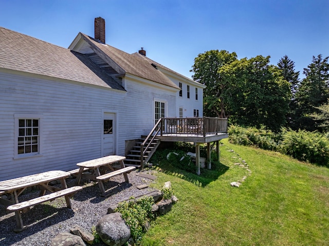 rear view of house with a wooden deck and a lawn