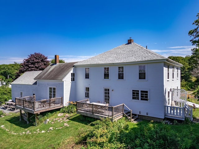 rear view of house featuring a deck and a lawn