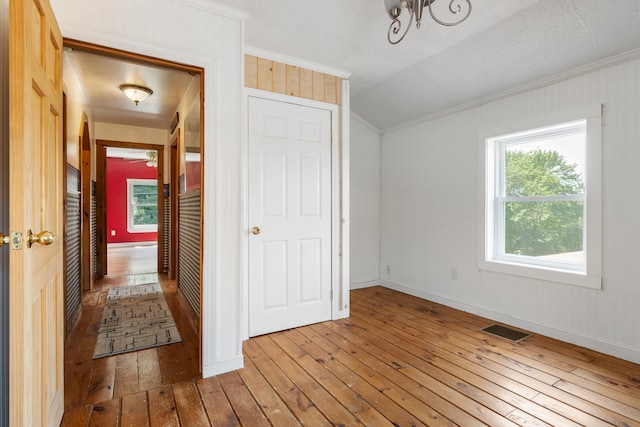 interior space with a textured ceiling, ornamental molding, and hardwood / wood-style floors