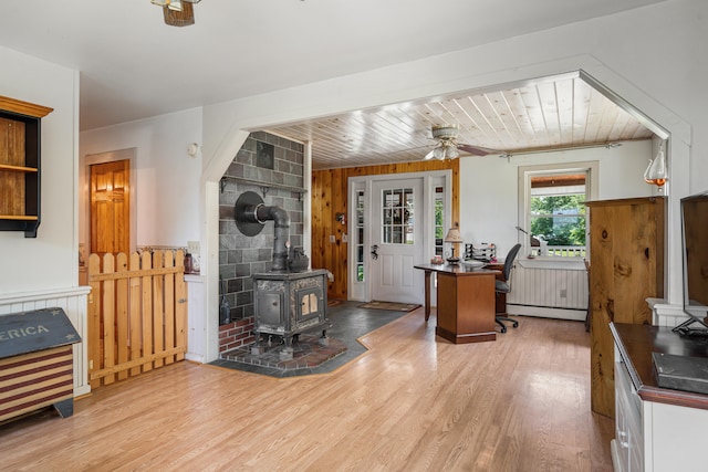 kitchen featuring a baseboard heating unit, ceiling fan, a wood stove, and hardwood / wood-style floors