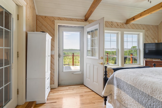 bedroom featuring light hardwood / wood-style floors, vaulted ceiling with beams, and multiple windows