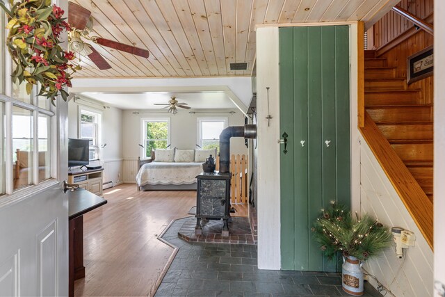 entryway with a baseboard radiator, wooden ceiling, dark hardwood / wood-style floors, a wood stove, and ceiling fan