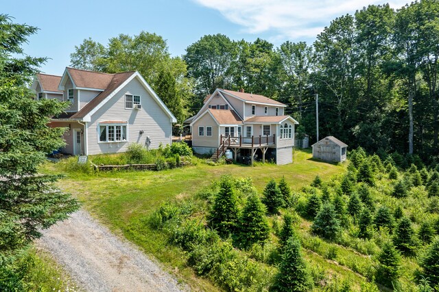 back of property with an outdoor structure, a deck, and a lawn