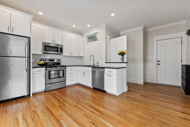 kitchen with stainless steel appliances, white cabinetry, and crown molding