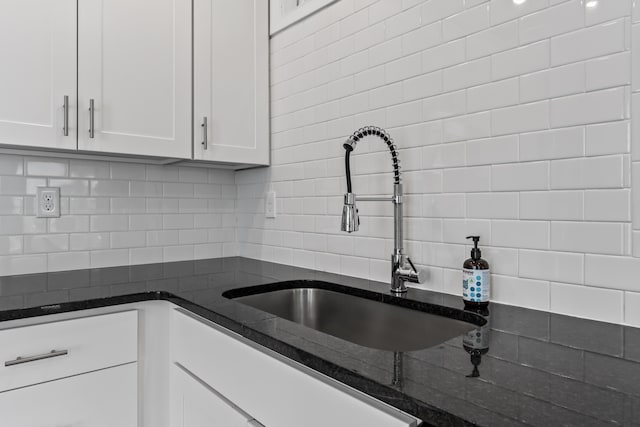 kitchen featuring white cabinets, dark stone countertops, sink, and tasteful backsplash