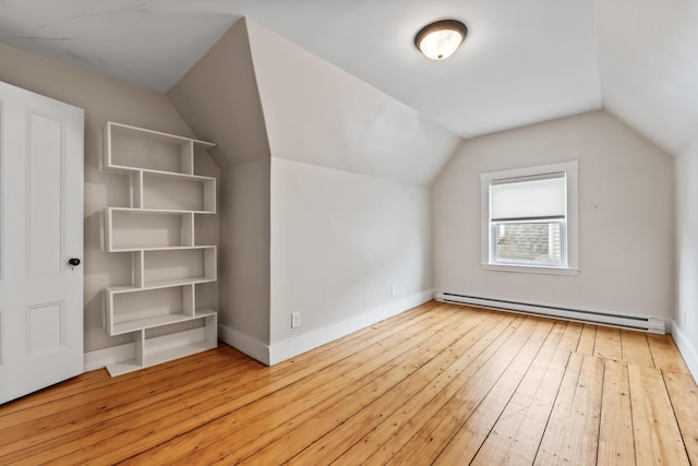 additional living space featuring vaulted ceiling, light hardwood / wood-style flooring, and a baseboard heating unit