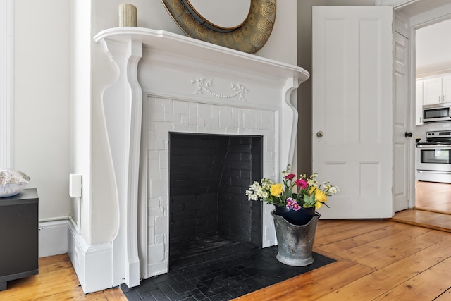 details with electric range, hardwood / wood-style floors, and a brick fireplace